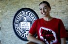 Maggie Kline stands in front of Illinois State University emblem in Bone Student Center wearing Fear the Bird shirt.