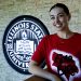 Maggie Kline stands in front of Illinois State University emblem in Bone Student Center wearing Fear the Bird shirt.