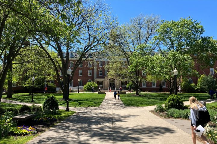 Fell Hall in the distance as seen from across the Quad in late spring 2023, with students walking to and from class.