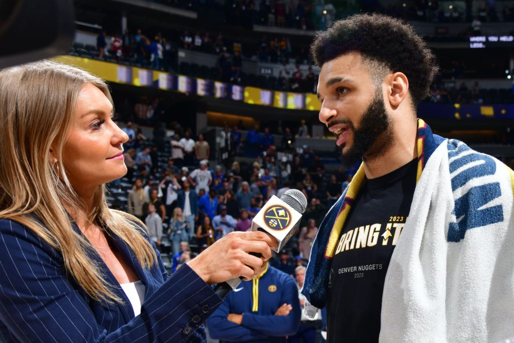 Kate Winge holds microphone out while interviewing Jamal Murray