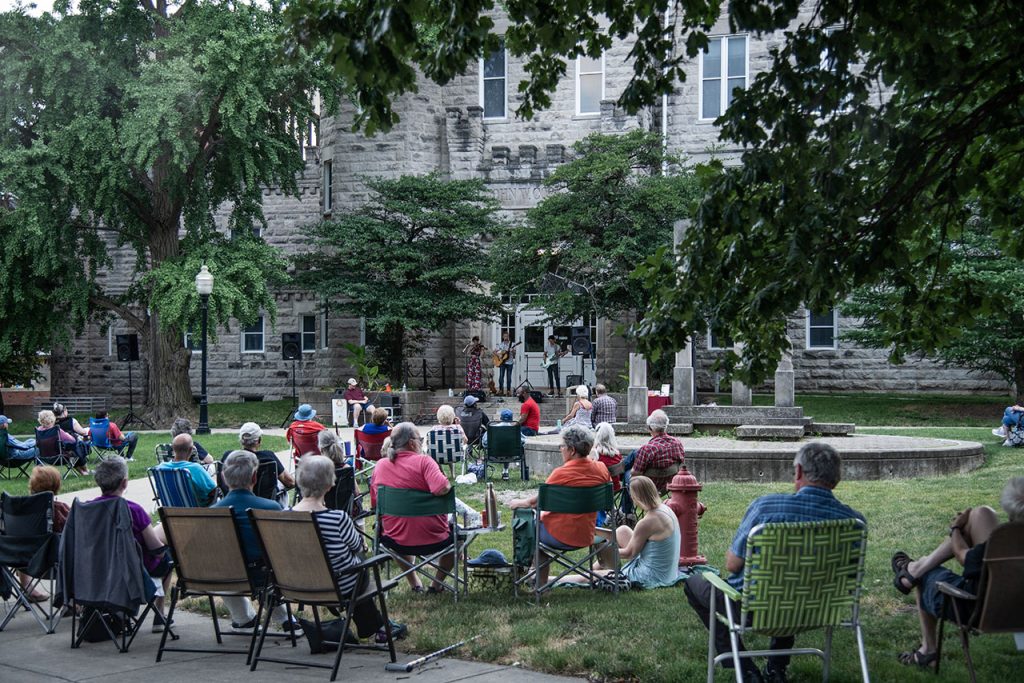 People seated on the Quad enjoying music with Cook Hall in the background