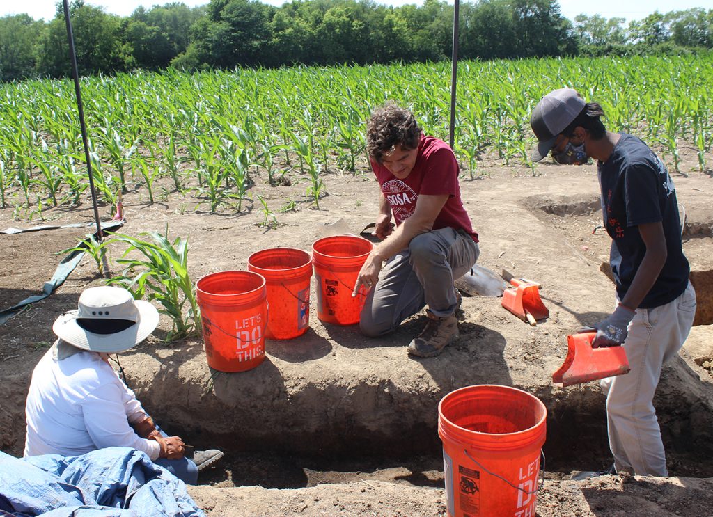 Dr. Logan Miller speaks with graduate student Anastasia Ervin and senior while they dig into a home buried at the Noble-Wieting archaeological site.