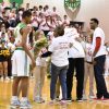 A basketball player is greeted by his family on the court during Senior Night