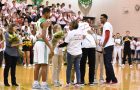 A basketball player is greeted by his family on the court during Senior Night