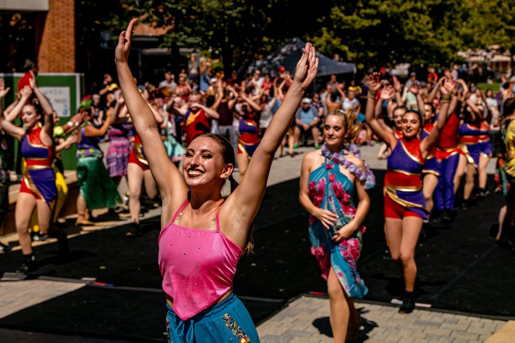 Performers extend their arms while a crowd watches