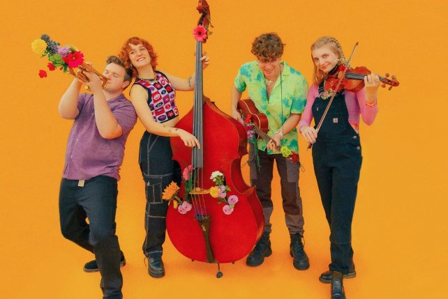Image of the members of Good Morning Bedlam. Orange backdrop, each holding instruments.