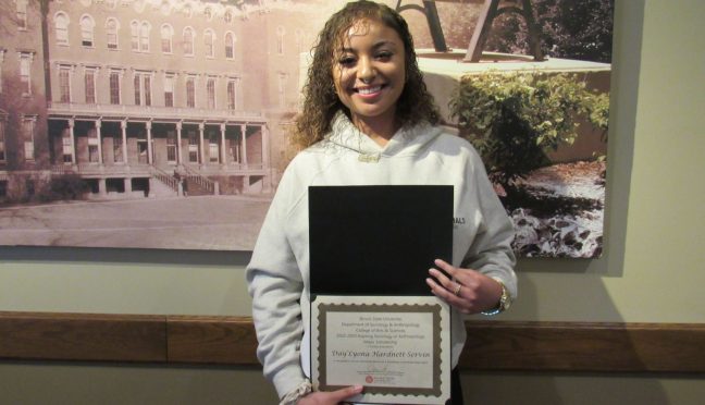 A young woman holding up a certificate