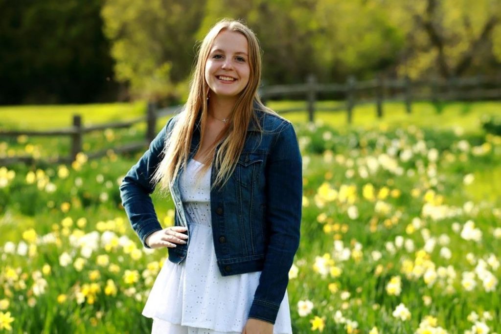 student posed in a field of flowers