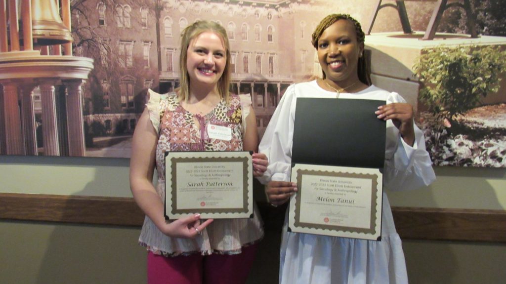 Two young women holding up certificates