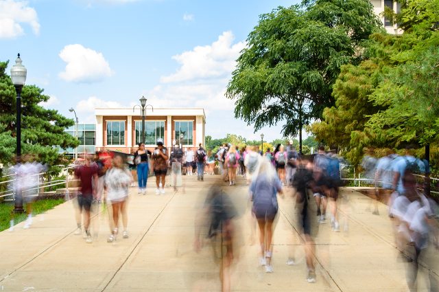 slow exposure photo of students walking through campus