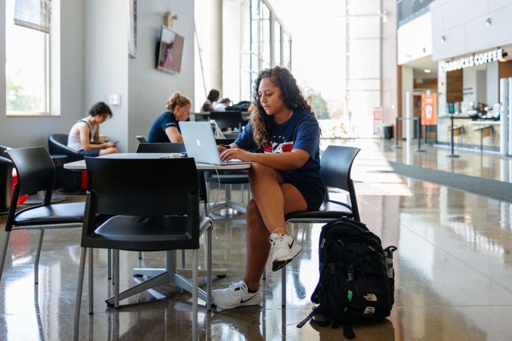 A student studying with their laptop inside the Student Fitness Center front area.