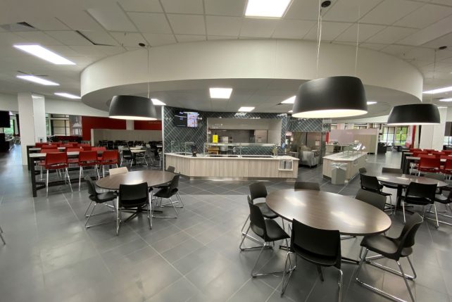 Tables and chairs in front of the pizza and pasta serving station in Watterson Dining Commons.