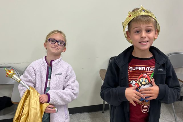 Two children, one with a crown and one with a scepter during a Creative Drama activity.