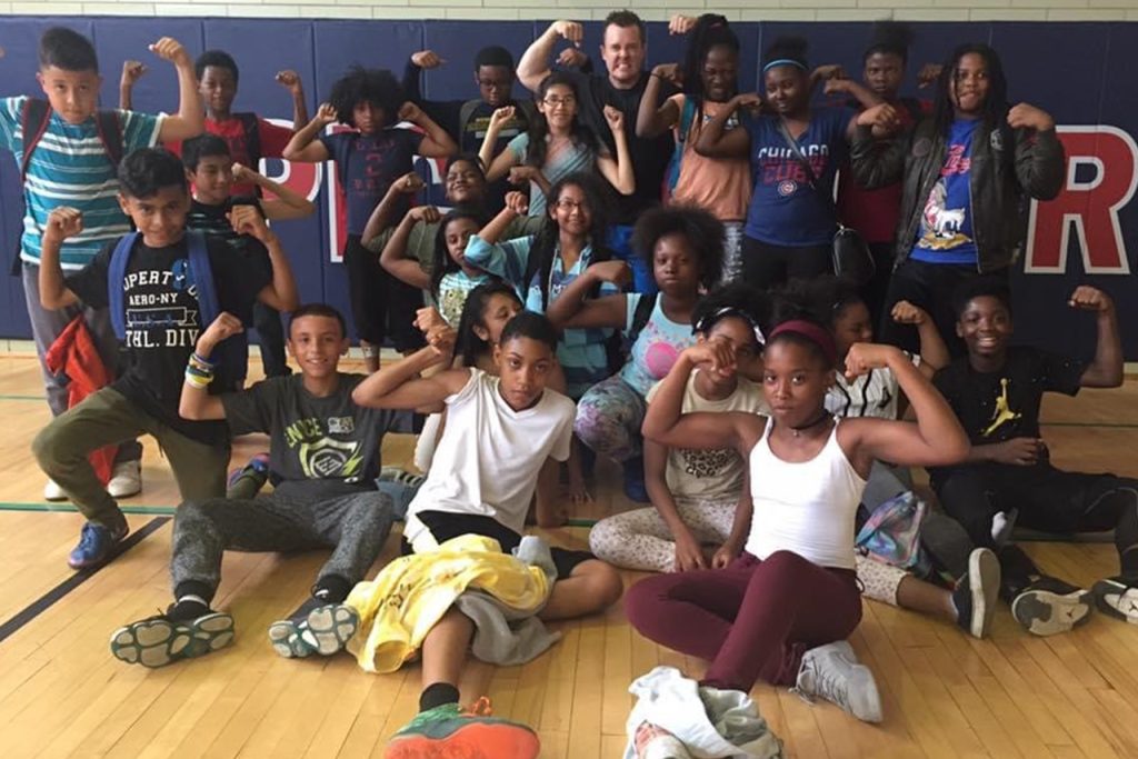 class of kids in a gym, flexing