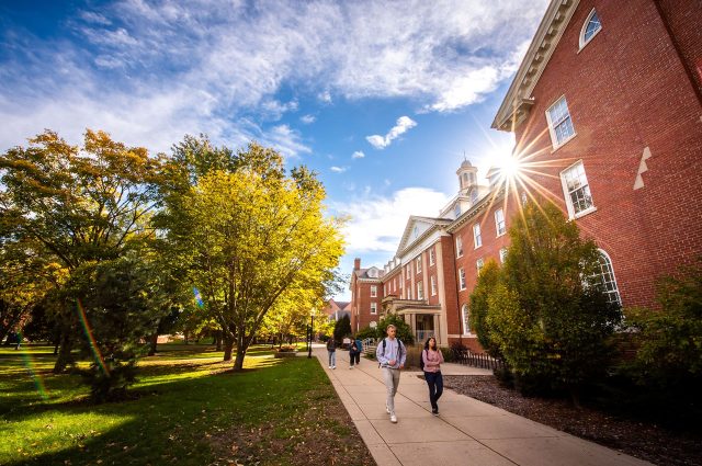 Students walk on the Quad outside of Fell Hall on a sunny fall day.