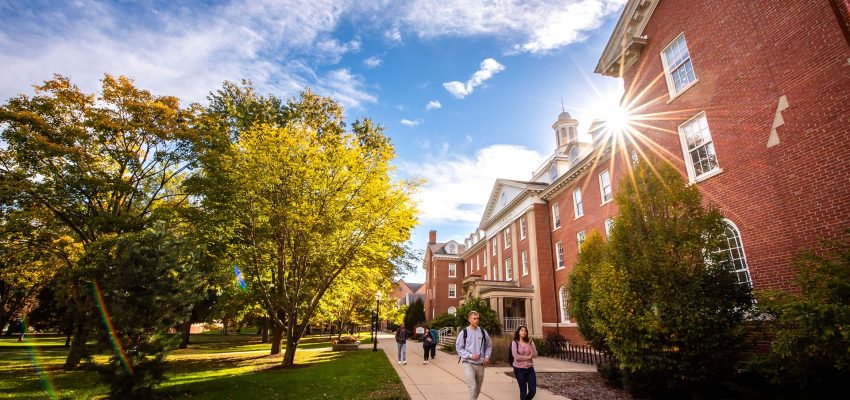 Students walk on the Quad outside of Fell Hall on a sunny fall day.