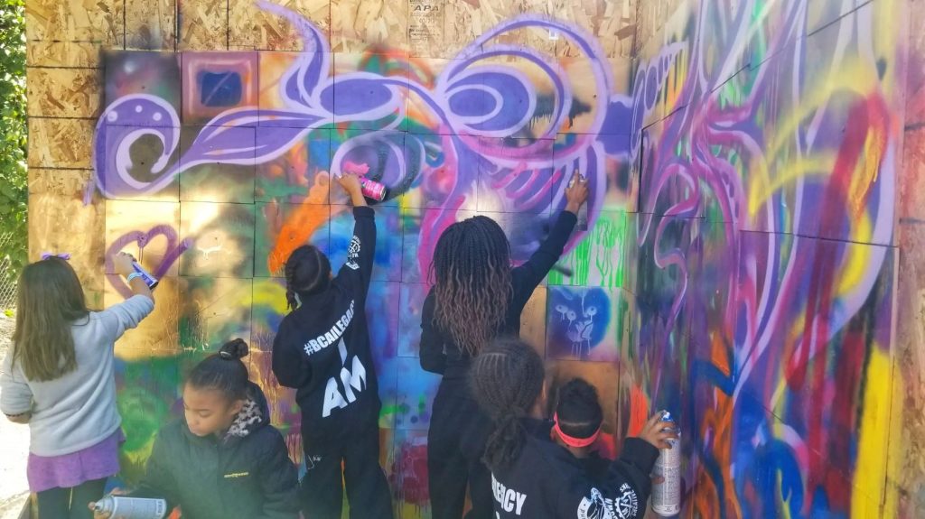 Children spraying graffiti art onto canvases