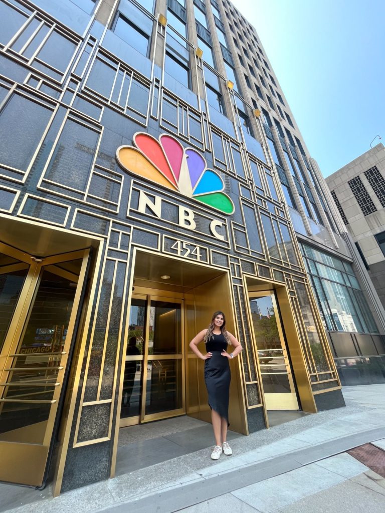A student posing in front of the NBC Universal building in Chicago, IL.