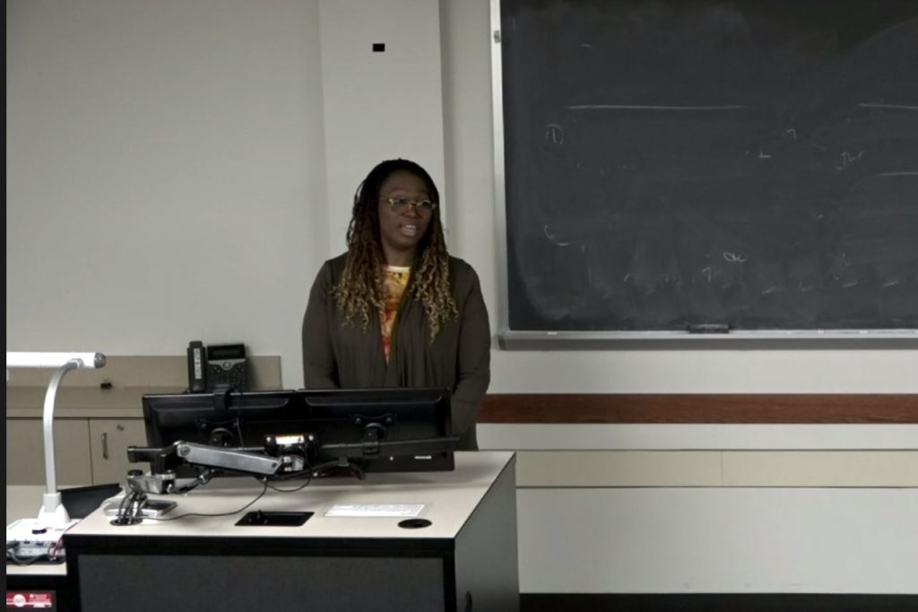 A woman standing in front of a computer leading a presentation