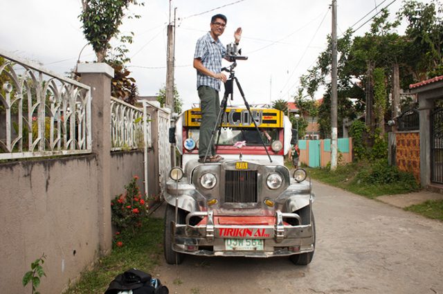 Jason Reblando standing on top of a car with a tripod in the Philippines