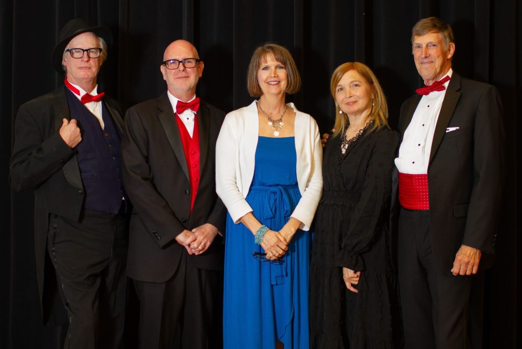 The founding members of of the Firehouse Theatre. All are dressed in back and red except for Janet Wilson in the middle who is dressed in blue and white.