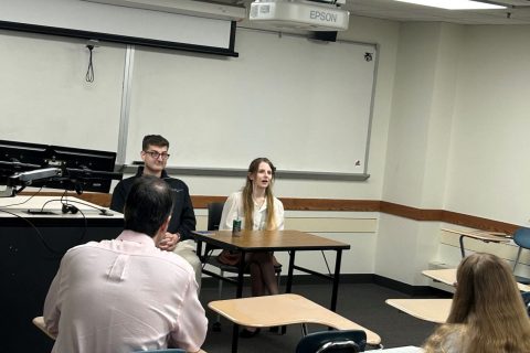 Two alumni sitting at a table and speaking with students