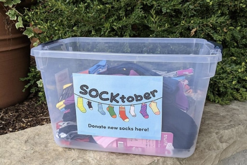 A plastic container with the word "SOCKtober" on its side has socks in it