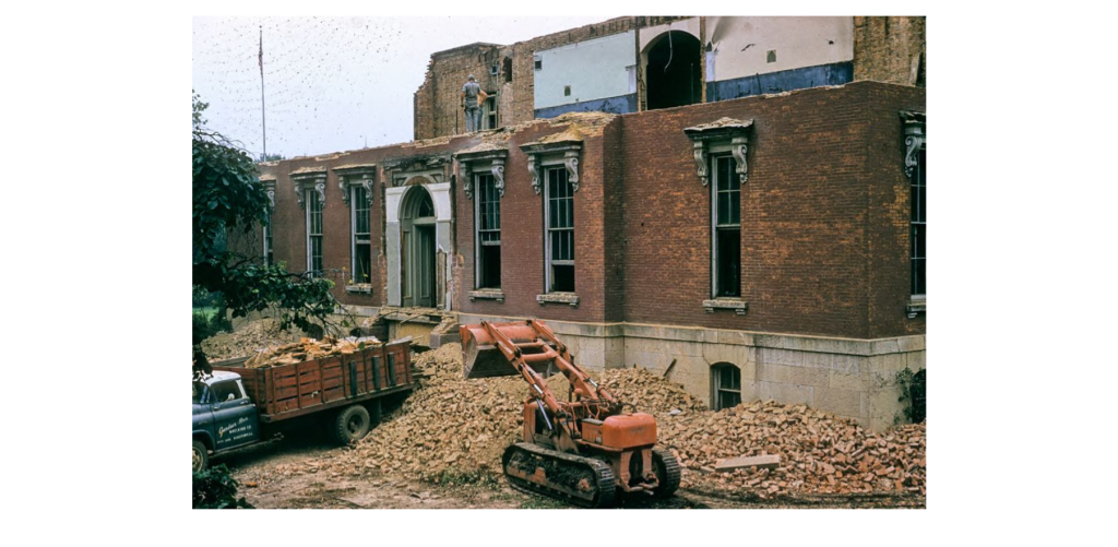 A bulldozer and dump truck work to demolish the Old Main building.