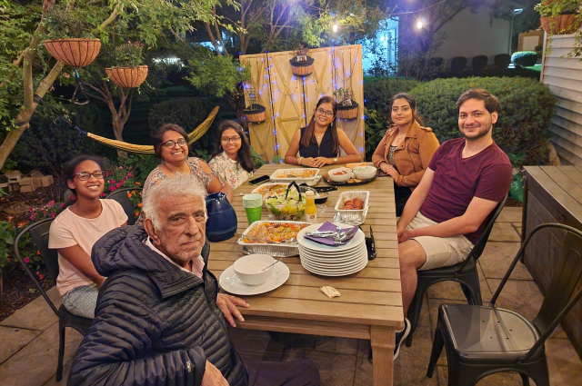 A group of seven people smiling for a picture as they enjoy dinner at a restaurant
