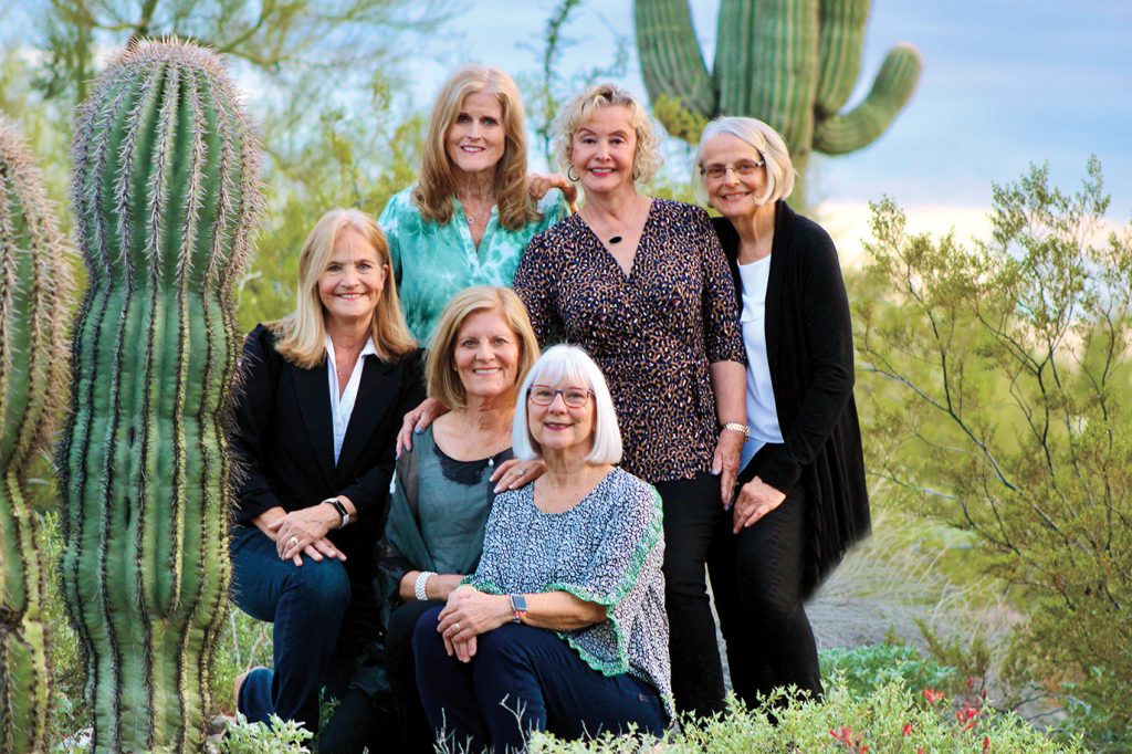 Alumni group posed in a desert setting surrounded by cacti
