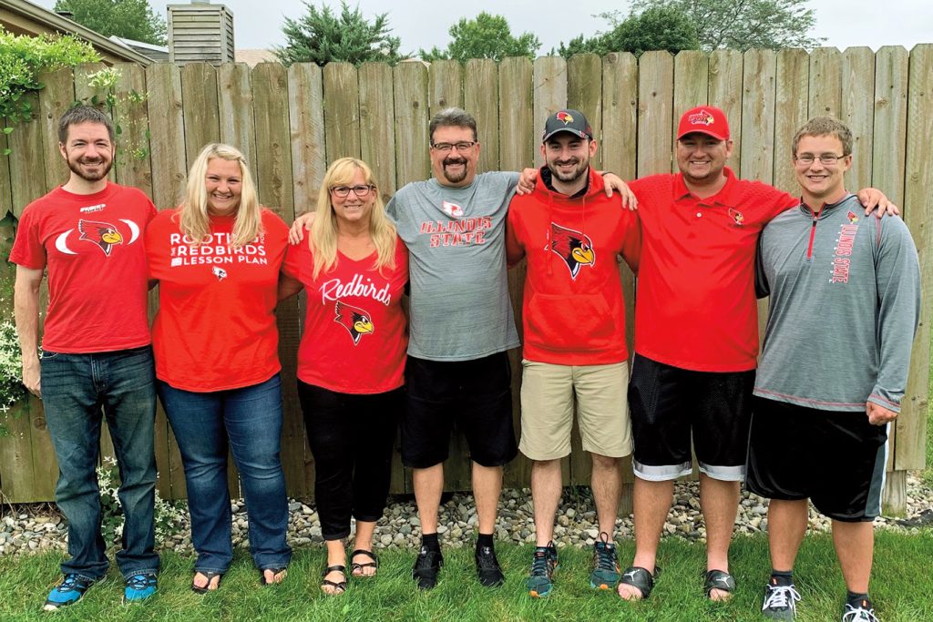 a family standing in a row, arms on each others shoulders, all wearing Illinois State shirts