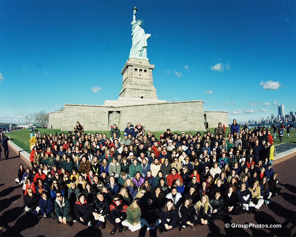 A group of people standing in front of the Statue of Liberty