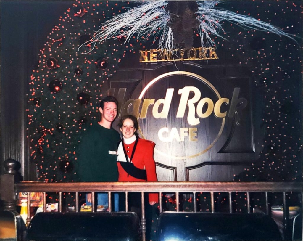 Two students (one wearing a red and white marching band uniform) pose in front of a "Hard Rock Cafe New York" sign