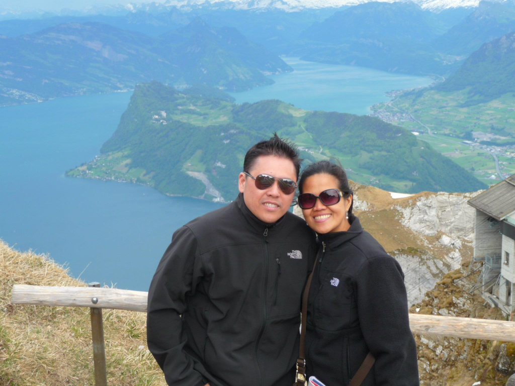 Reyes and her husband smile on a mountain in Switzerland.