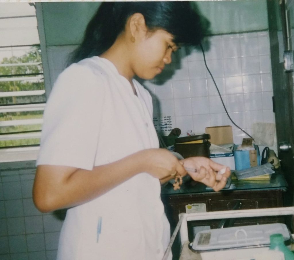 A young Reyes uses a syringe at her first nursing job as a volunteer. 