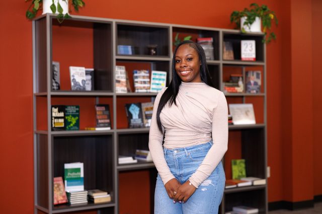 Kiara Mills stands in front of a bookshelf in the Multicultural Center