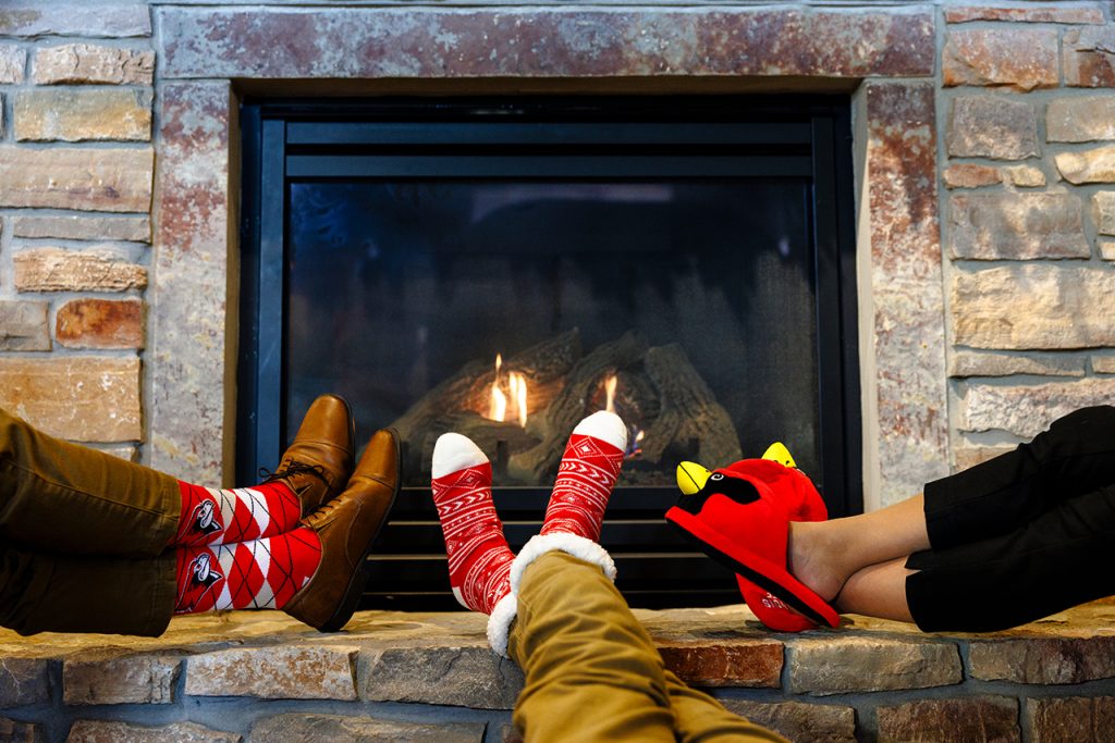 people wearing redbird merch socks/slippers resting on fireplace