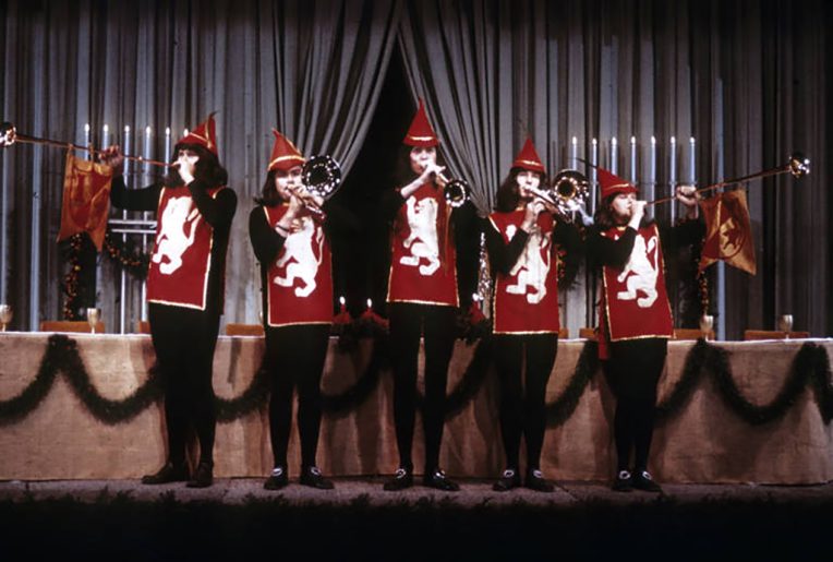 Five people wearing costumes play instruments