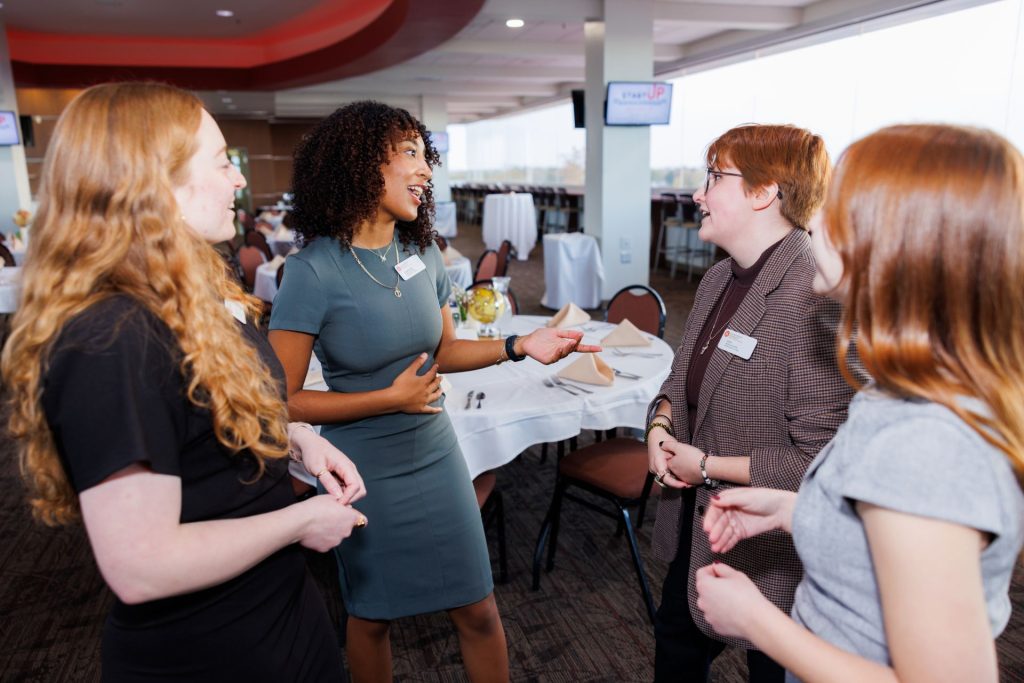 Angelina Ruiz talks with Kenzie Reimers,  an external relations assistant director at WZND, Ellanore Foltz, a senior intern at WZND, and Cami Serrahn, assistant director of public relations for WZND, in the Aaron leech club as the event begins. 
