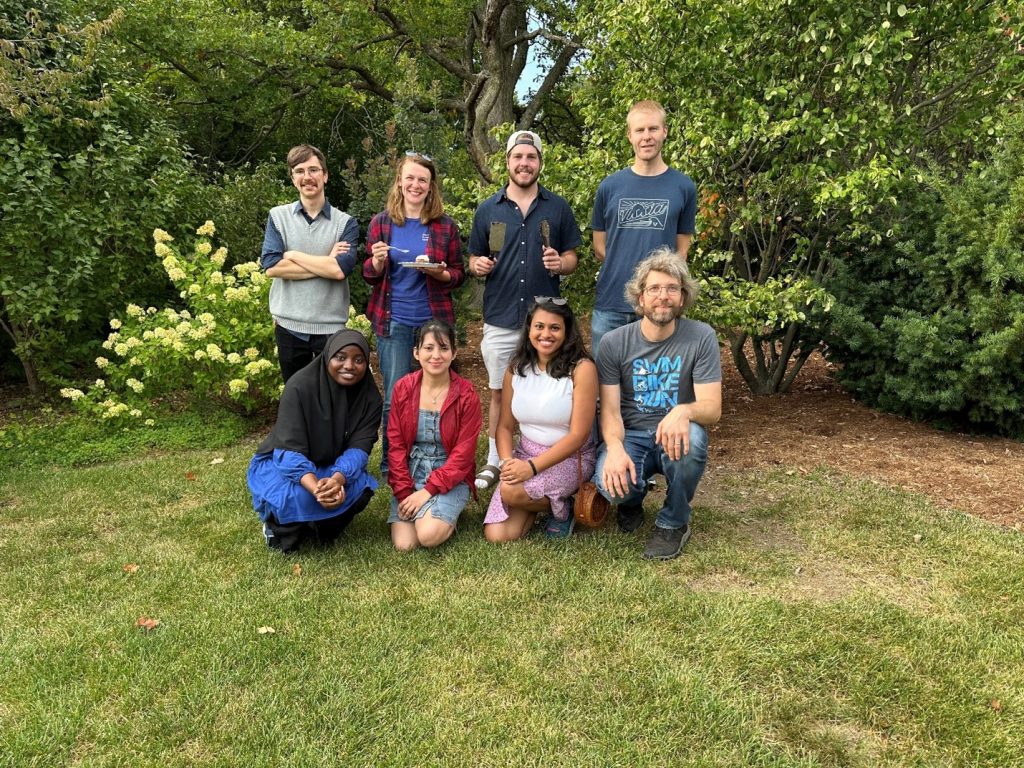 Eight executive members of Phi Sigma Beta Lambda pose for a group photo outdoors. 
