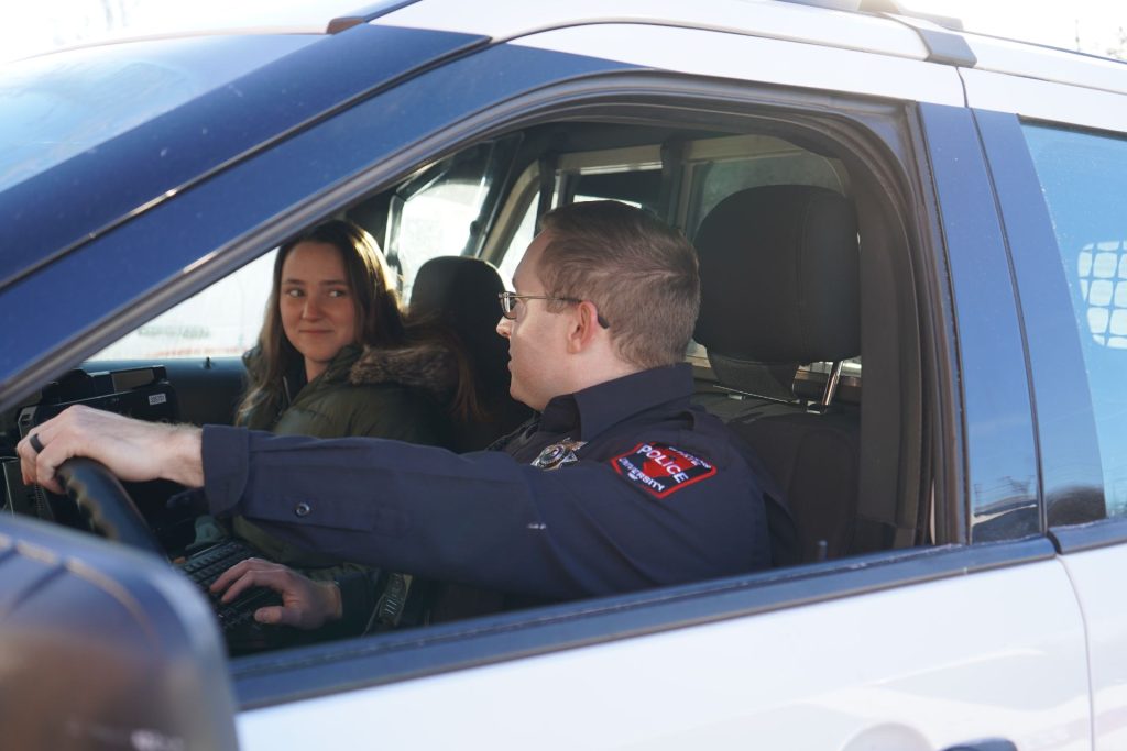 An officer and co-Responder sit together in a police squad car.