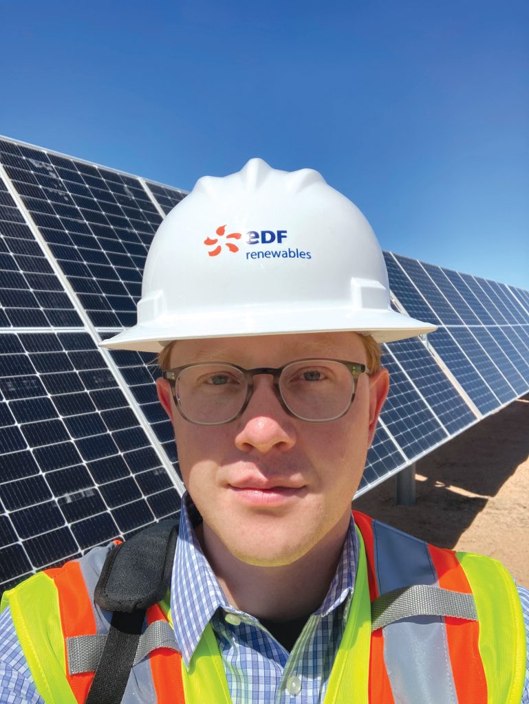 person wearing a hard hat standing in front of solar panels 