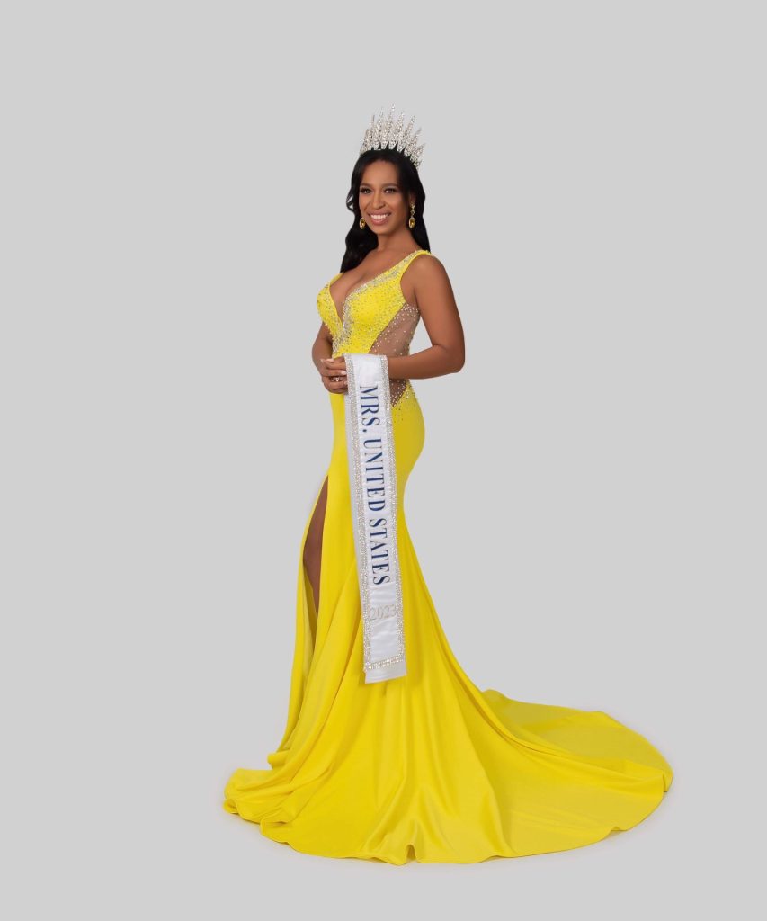 Toby Atkinson wearing a yellow dress with a crown and a Mrs. United States sash