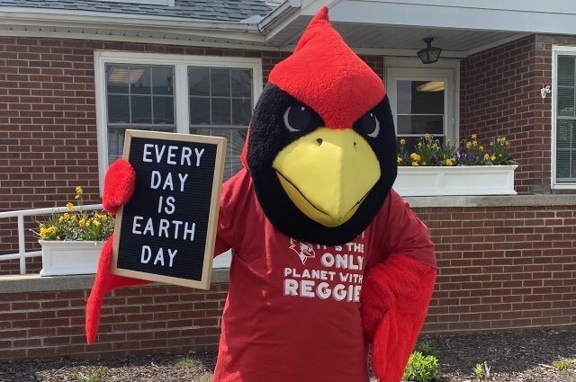 Reggie Redbird holding sign that says every day is earth day