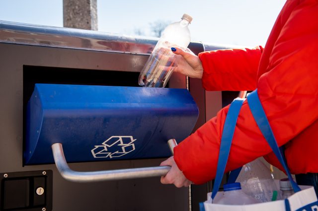 hands opening recycling bin and putting empty water bottle in
