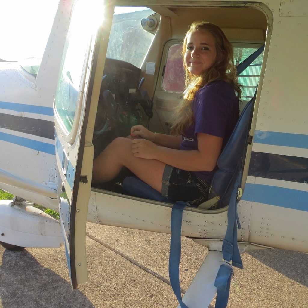 A young girl sitting in the front seat of a plane.
