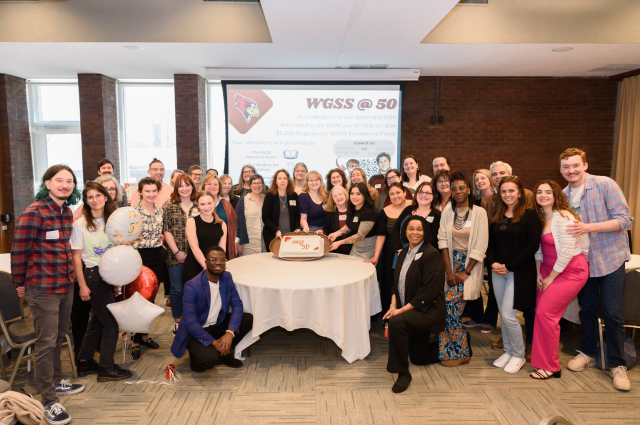 WGSS faculty, staff, and students pose around a 50th anniversary cake.