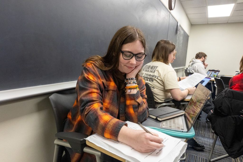 Senior English major Emily Mepham works on an in-class activity wearing an evermore flannel and her folklore and evermore bracelets in honor of the albums they’re discussing.