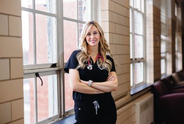 Doctoral nursing student posing in a school hallway against a set of windows