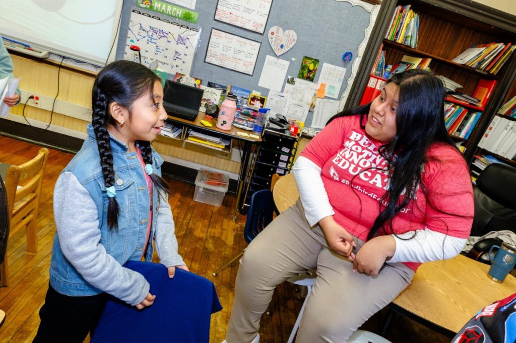 Yehiri Gonzalez smiles while listening to an elementary school student tell her a story.